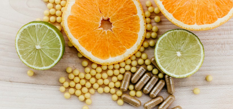 Tranches d’agrumes et perles de compléments alimentaires sur une surface en bois